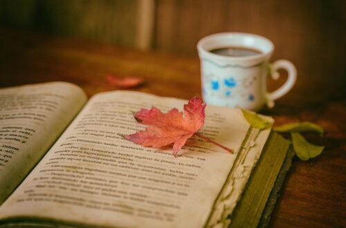 old book with a leaf on it and a cup of coffee sitting next to it